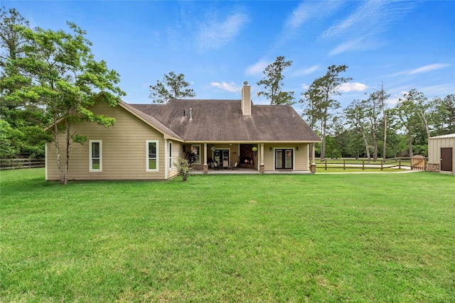back of property with a patio, a fenced backyard, french doors, a chimney, and a lawn