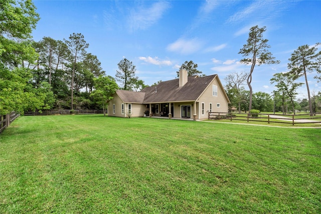 rear view of property with a lawn, a fenced backyard, and a chimney