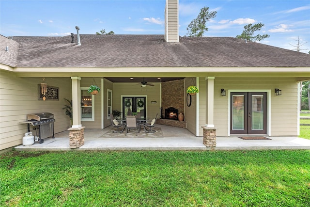 rear view of property featuring a ceiling fan, french doors, a chimney, a lawn, and a shingled roof