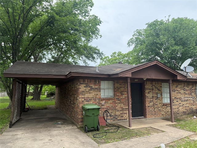 single story home featuring roof with shingles, an attached carport, concrete driveway, and brick siding