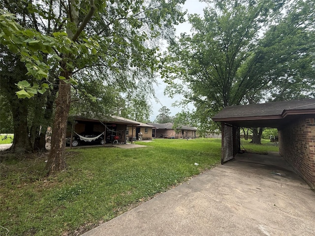 view of yard with concrete driveway and a carport