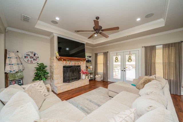 living room with french doors, a ceiling fan, wood finished floors, a tray ceiling, and visible vents