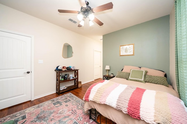 bedroom featuring baseboards, ceiling fan, visible vents, and wood finished floors
