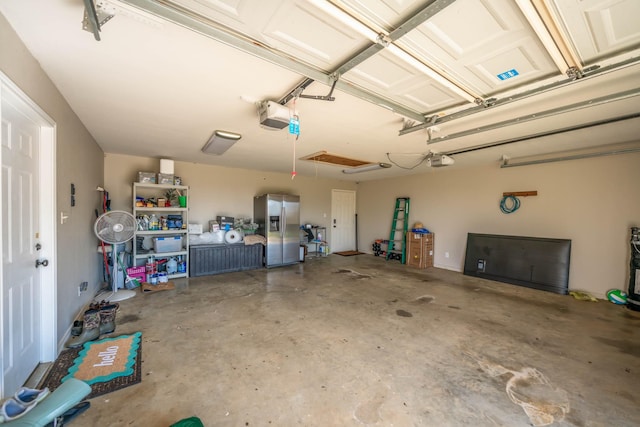 garage with stainless steel fridge with ice dispenser and a garage door opener