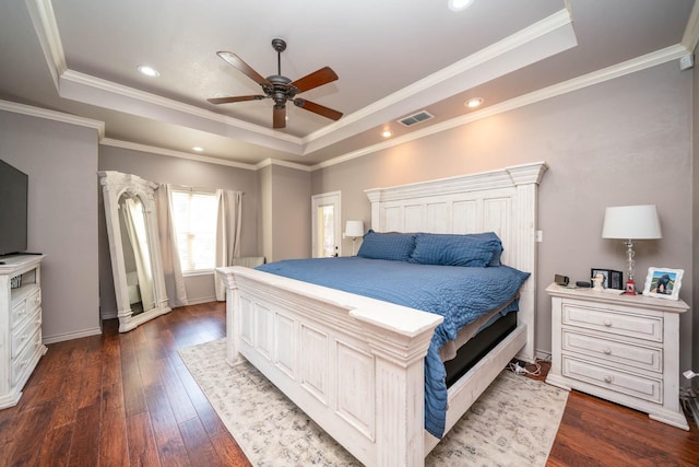 bedroom featuring baseboards, a tray ceiling, dark wood-style flooring, and visible vents