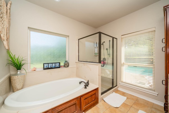 bathroom featuring tile patterned flooring, a wealth of natural light, a garden tub, and a stall shower