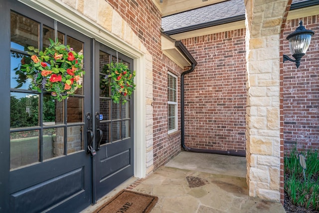 view of exterior entry featuring brick siding and french doors