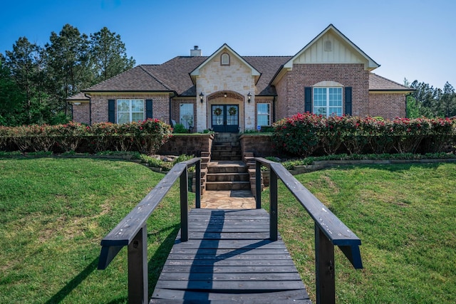 view of front of property featuring brick siding, a front lawn, board and batten siding, and french doors