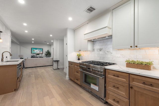 kitchen featuring visible vents, tasteful backsplash, a sink, light wood-style flooring, and appliances with stainless steel finishes