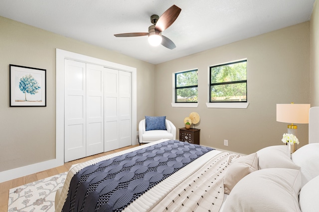 bedroom with a closet, light wood finished floors, ceiling fan, and baseboards