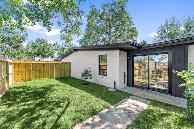 rear view of property featuring fence, a yard, and brick siding