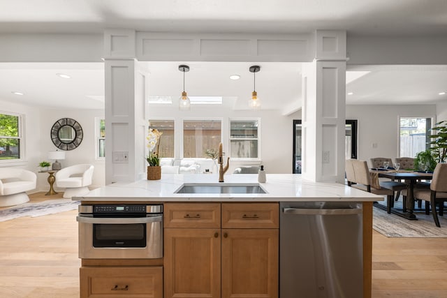 kitchen with open floor plan, a sink, light wood-style flooring, appliances with stainless steel finishes, and a wealth of natural light
