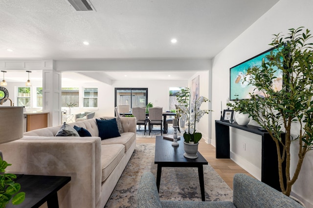 living area featuring light wood-style floors, baseboards, recessed lighting, and visible vents