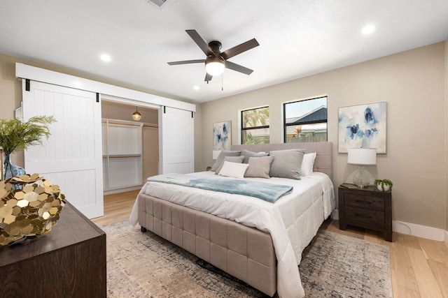 bedroom featuring baseboards, ceiling fan, recessed lighting, a barn door, and light wood-style flooring