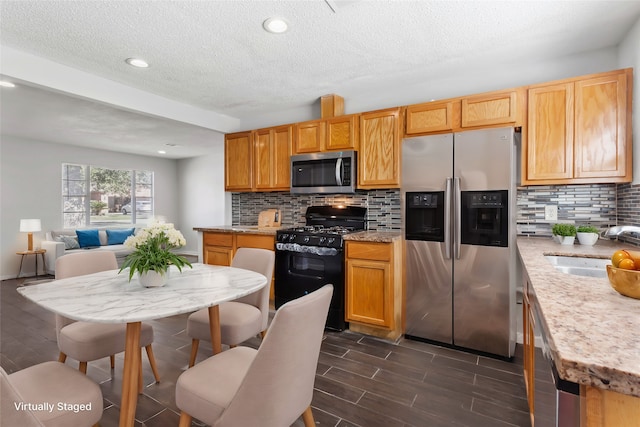 3450 Lydia St, Houston, TX 77021 - kitchen with decorative backsplash, dark wood-style flooring, a textured ceiling, a sink, and stainless steel appliances