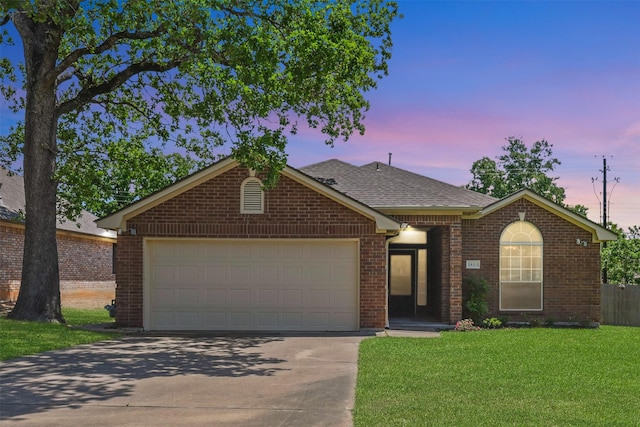 single story home featuring roof with shingles, an attached garage, a front lawn, brick siding, and concrete driveway