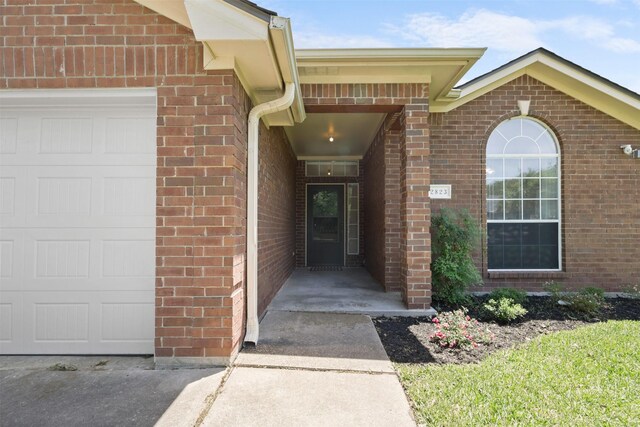 doorway to property featuring brick siding and an attached garage