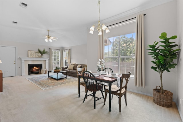 carpeted dining area featuring ceiling fan with notable chandelier, a tile fireplace, and visible vents