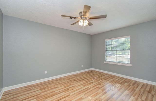 spare room with a ceiling fan, baseboards, a textured ceiling, and light wood-type flooring