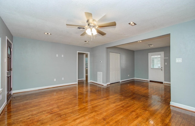 empty room featuring baseboards, ceiling fan, visible vents, and wood finished floors
