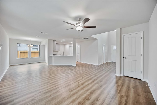 unfurnished living room with baseboards, visible vents, light wood-style flooring, and ceiling fan with notable chandelier