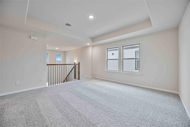 carpeted empty room with recessed lighting, a tray ceiling, visible vents, and baseboards