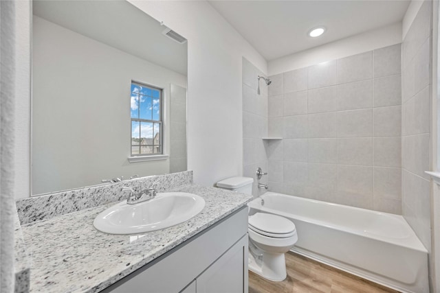 bathroom featuring shower / bathing tub combination, visible vents, wood finished floors, vanity, and toilet