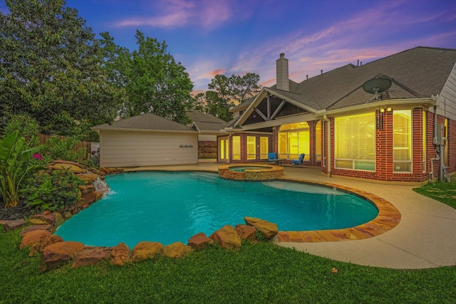 pool at dusk with a patio, a pool with connected hot tub, and fence