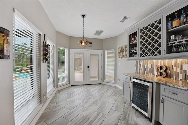 bar featuring a dry bar, beverage cooler, french doors, decorative light fixtures, and visible vents