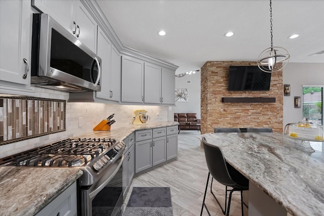 kitchen featuring decorative backsplash, gray cabinets, appliances with stainless steel finishes, and open floor plan
