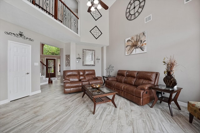 living area featuring ceiling fan, visible vents, baseboards, and a towering ceiling