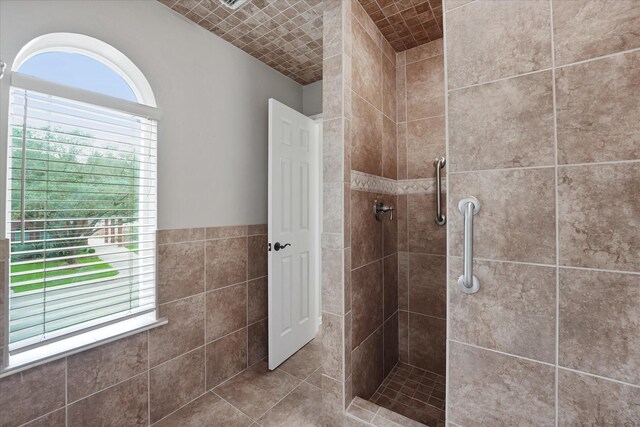 full bathroom featuring a tile shower and tile walls
