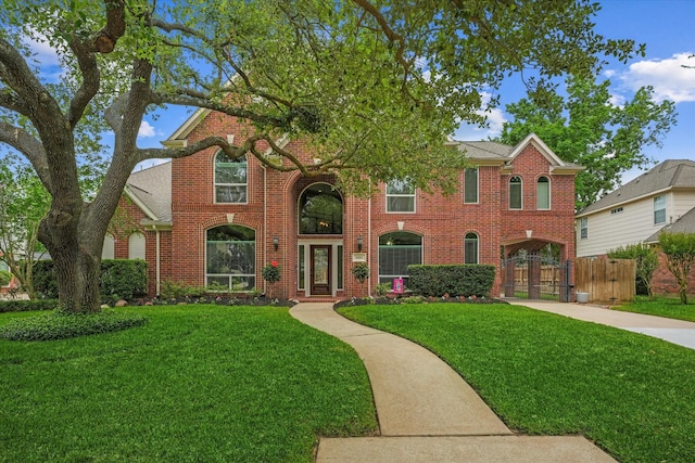 view of front facade with fence, driveway, a front lawn, and brick siding