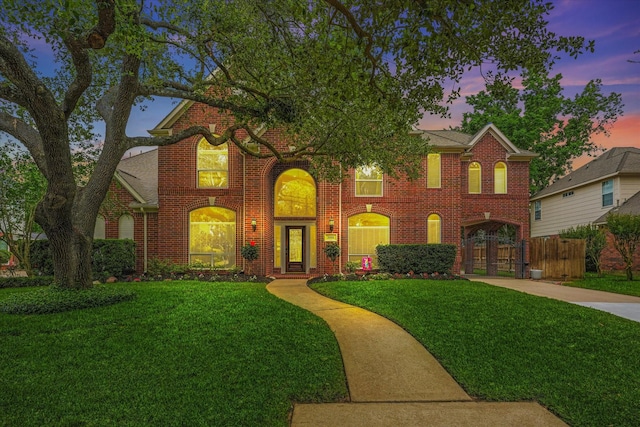 view of front of home featuring a yard, brick siding, fence, and driveway