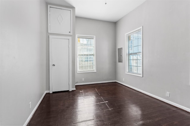 unfurnished bedroom featuring baseboards, multiple windows, and wood finished floors