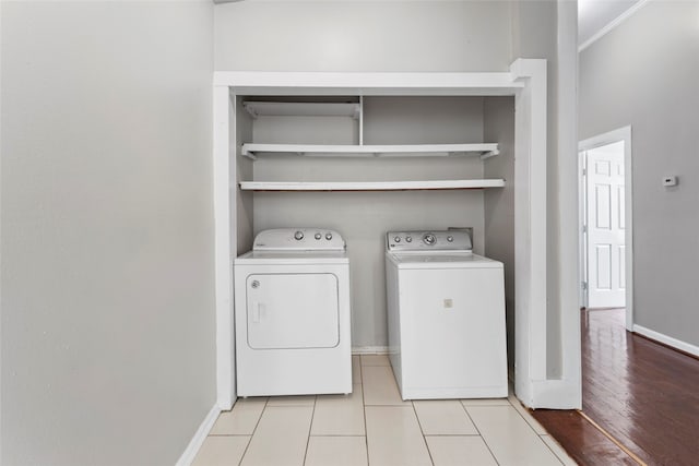 laundry room with laundry area, ornamental molding, baseboards, and washing machine and clothes dryer