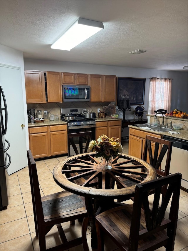 18207 Sea Branch Dr, Houston, TX 77084 - kitchen featuring a sink, appliances with stainless steel finishes, decorative backsplash, and light tile patterned flooring