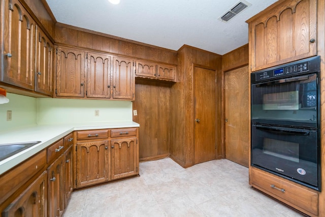kitchen featuring brown cabinets, dobule oven black, and visible vents