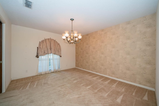 spare room featuring baseboards, visible vents, carpet flooring, and a notable chandelier