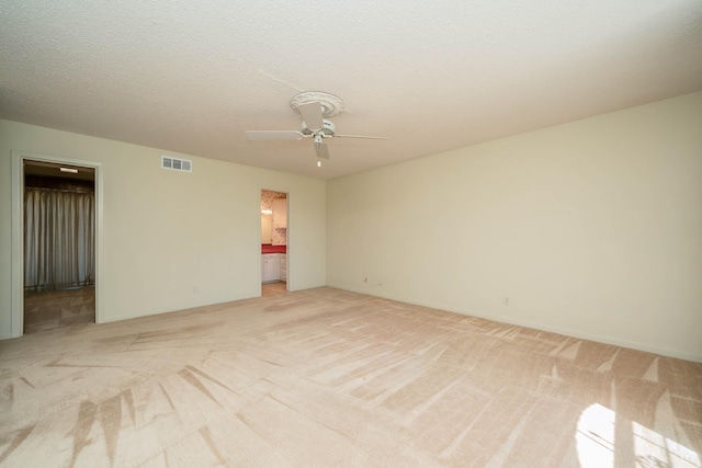 empty room featuring a ceiling fan, light colored carpet, and visible vents