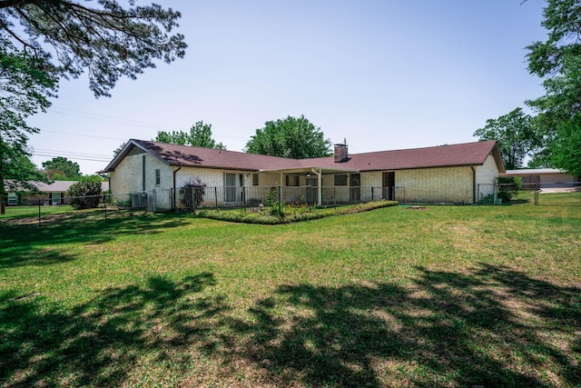 rear view of property with brick siding, fence, a yard, and a chimney