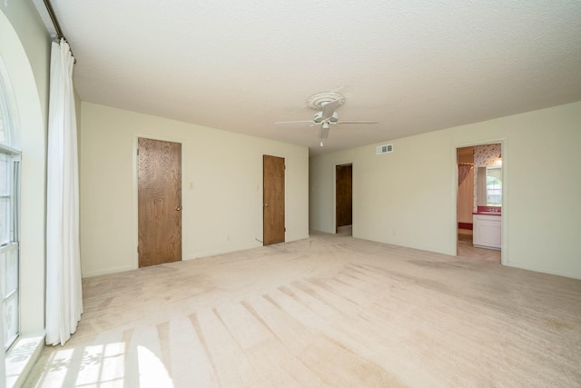interior space with a ceiling fan, multiple closets, visible vents, and light carpet