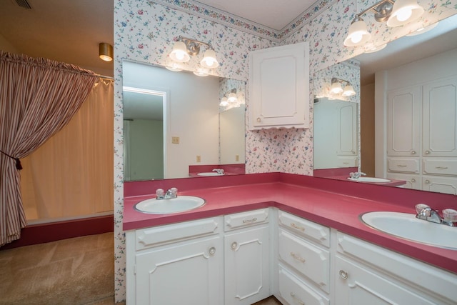 full bath with double vanity, a sink, and wallpapered walls
