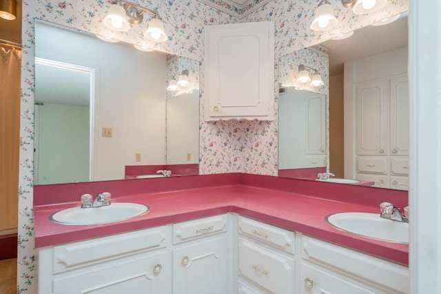 bathroom featuring a sink, wallpapered walls, and double vanity