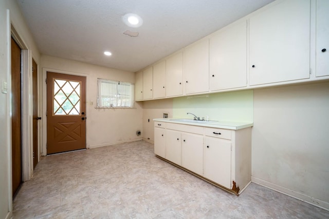 clothes washing area featuring washer hookup, electric dryer hookup, cabinet space, a sink, and light floors
