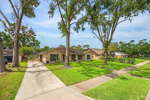 ranch-style home featuring fence, driveway, a front lawn, and stone siding
