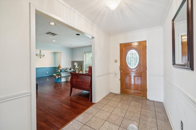 foyer featuring crown molding, baseboards, a chandelier, and visible vents