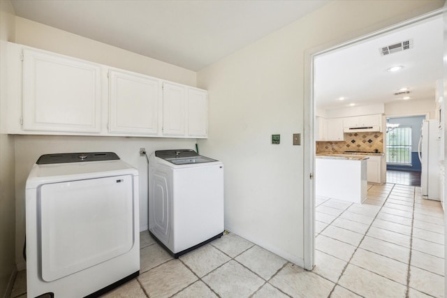 laundry area with washer and dryer, light tile patterned flooring, visible vents, and cabinet space
