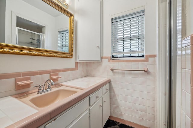 bathroom with vanity, a shower with shower door, and tile walls