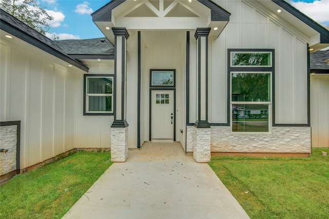 712 Sealy St, Clute, TX 77531 - view of exterior entry with a lawn, a shingled roof, and board and batten siding